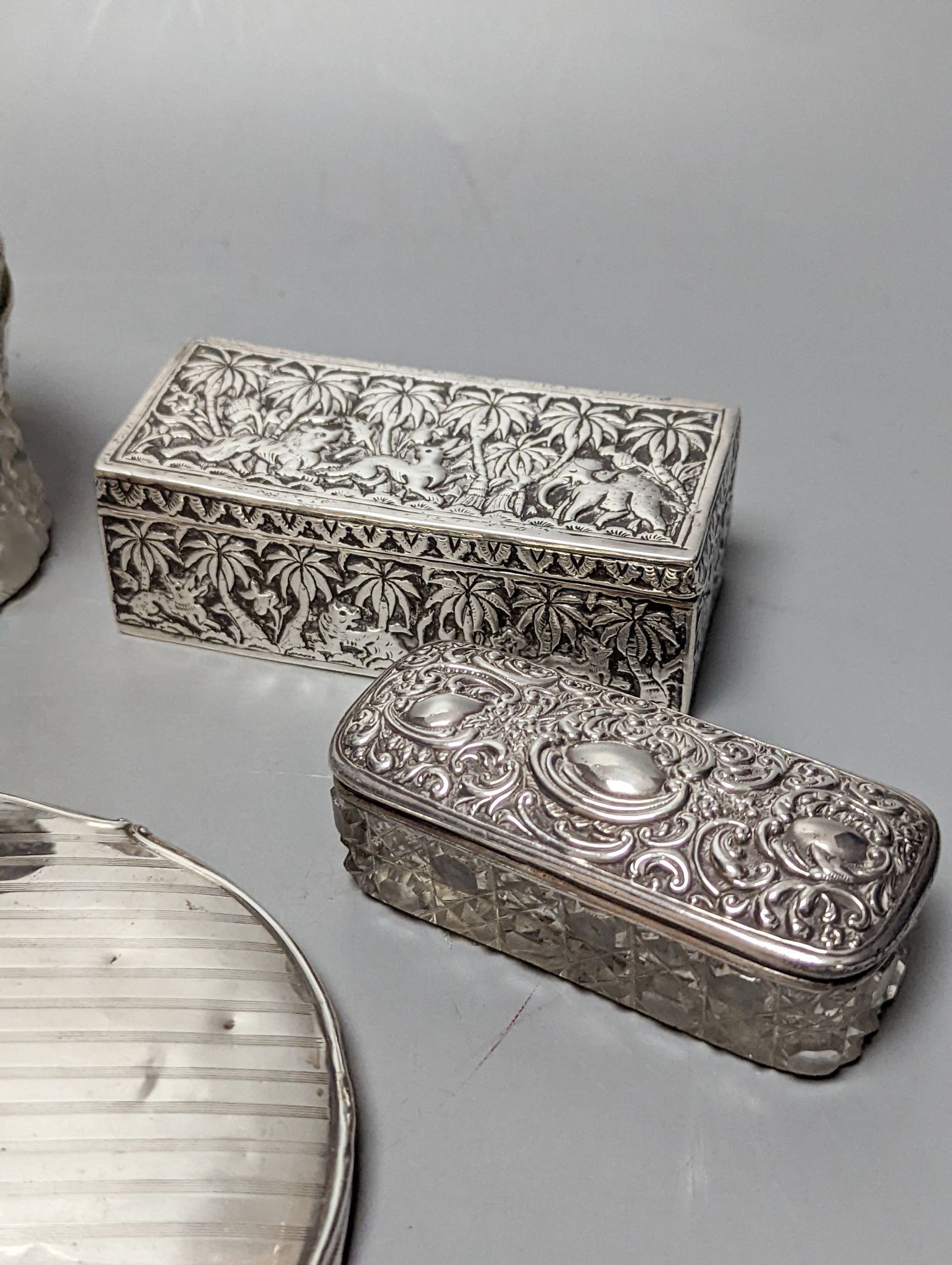 A silver mounted hand mirror, five assorted silver mounted glass toilet jars and an Indian white metal rectangular box.
